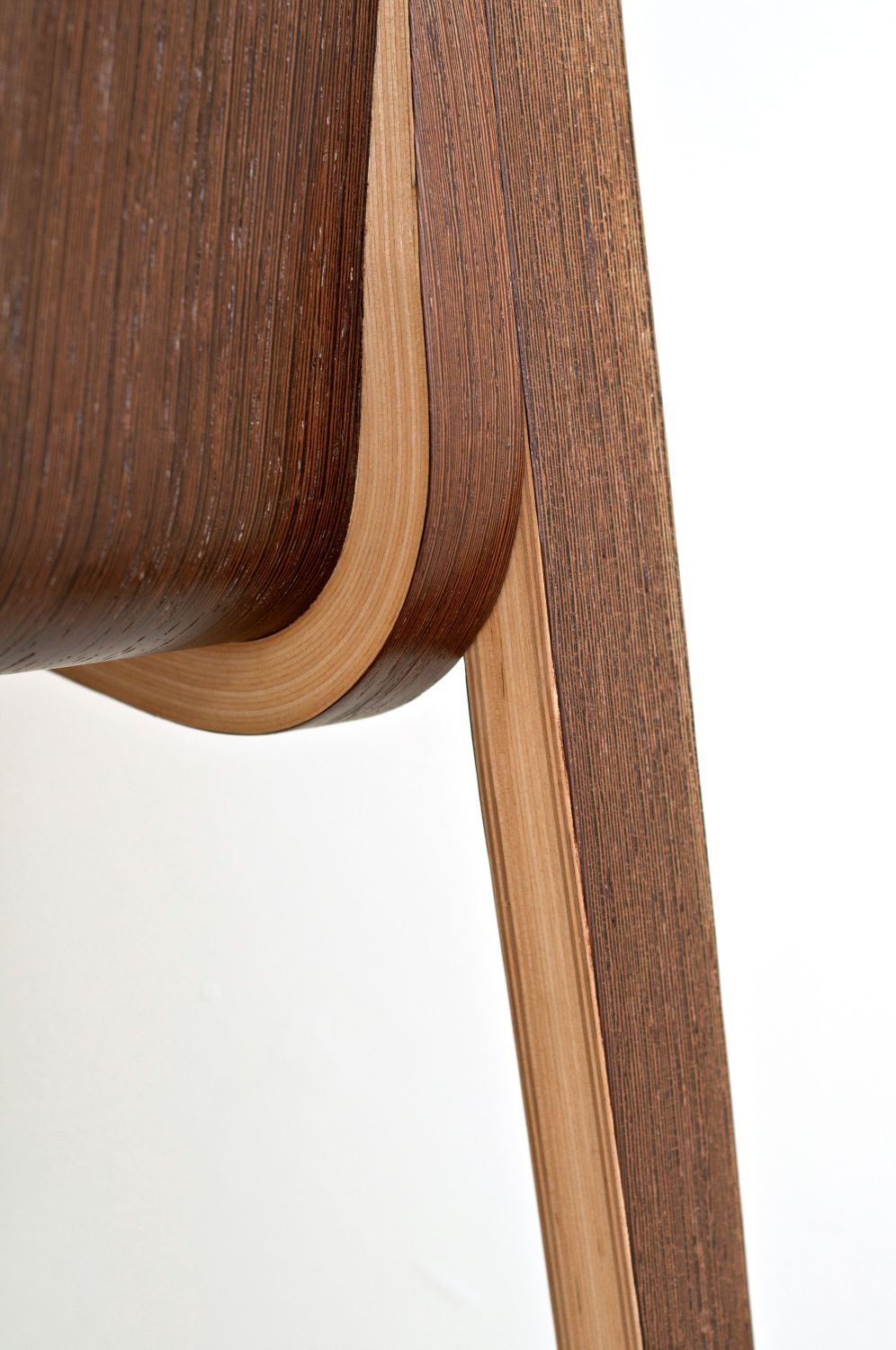 Detail FLOW: Übergang von Sitz zu Bein in gebogenem Formsperrholz mit Walnussfurnier