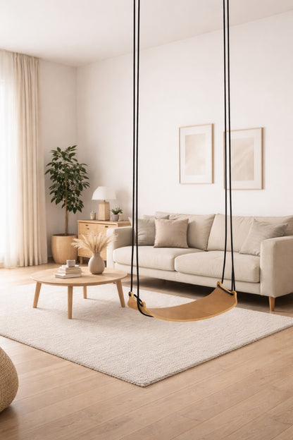 Minimalistische Indoor-Schaukel TUULAR aus hellem Holz mit schwarzen Seilen, hängend in einem modernen, hellen Wohnzimmer als stilvolles Sitzmöbel für Erwachsene.
