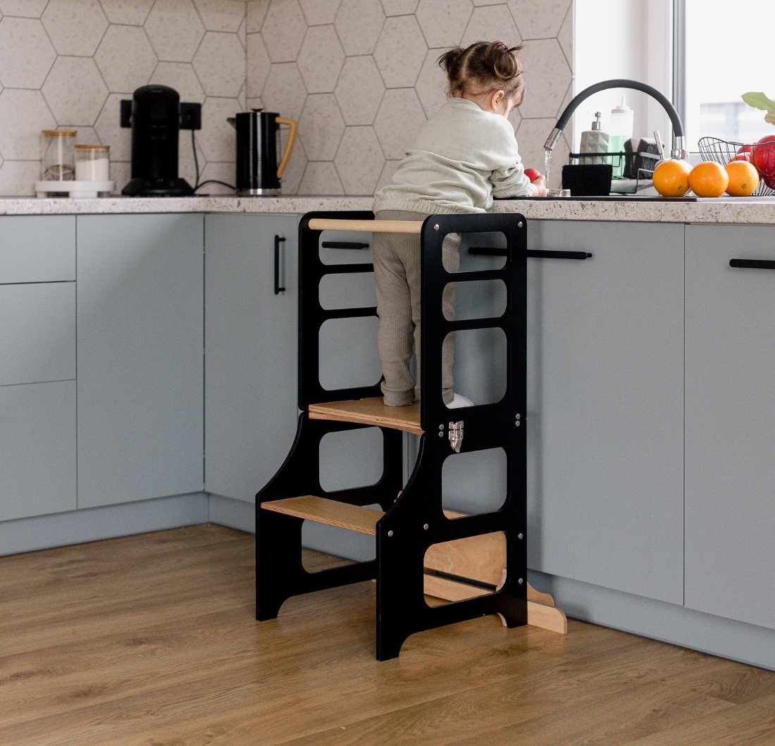 Kleines Mädchen steht im multifunktionalen 2-in-1 Lernturm & Kindertisch in skandinavischem Design in der Farbe schwarz, Hersteller: Duck Woodworks