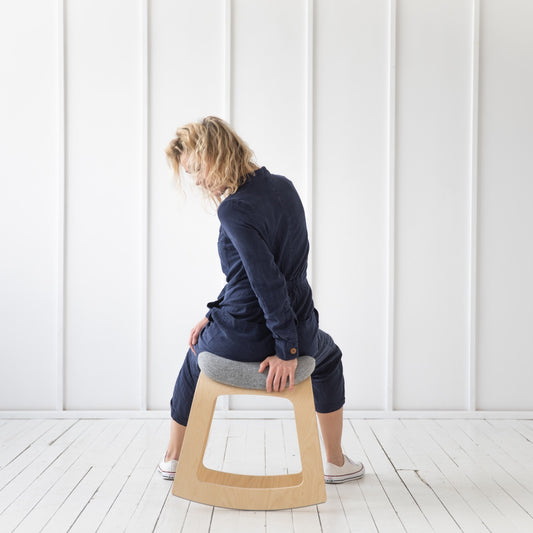 Junge Frau demonstriert den positiven Einfluss auf die Rückenmuskulatur beim Sitzen auf dem ergonomischen Bürohocker MUISTA in skandinavischem Stil 