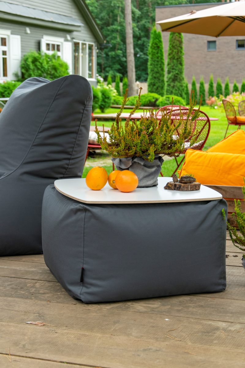 Sitzsack-Beistelltisch SOFT TABLE Dunkelgrau auf einer Holzterrasse mit Orangen, Hersteller: Slowdown