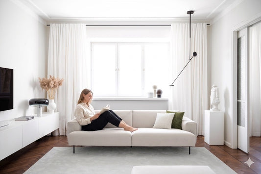 Sofa MOSS 205, auf dem eine Frau lesend sitzt, die Beine auf dem Polster, in einem hellen Wohnzimmer; Hersteller: Oot-Oot, Bild: KI-generiert