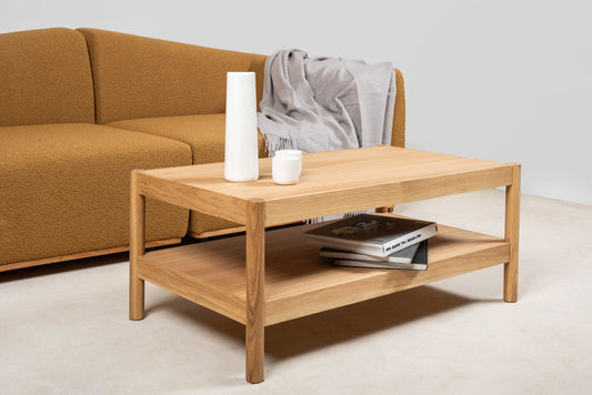 Couchtisch CITIZEN rechteckig mit Deko-Elementen und Büchern in der unteren Ablage vor einem Sofa. Hersteller: Emko