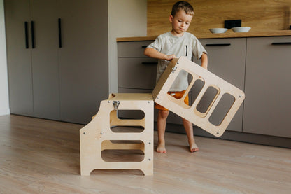 Ein Junge klappt den multifunktionalen 2-in-1 Lernturm & Kindertisch um in skandinavischem Design in der Farbe natur, Hersteller: Duck Woodworks